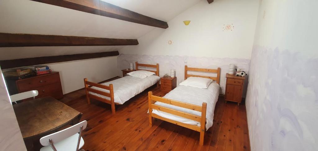 a bedroom with two beds and a table and chairs at charmante maison de village in Saint-Jean-du-Bruel