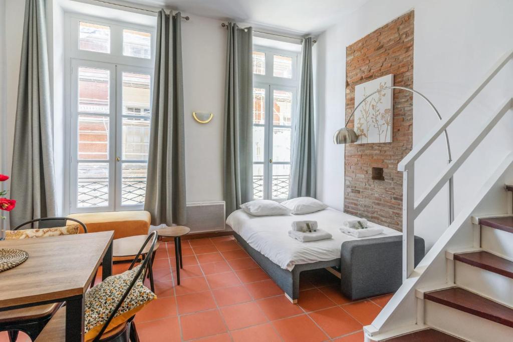 トゥールーズにあるVery nice duplex located on the main square - Toulouse - Welkeysのベッド、テーブル、椅子が備わる客室です。