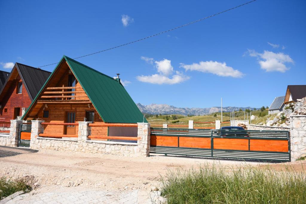 Cabaña de madera con techo verde y valla en Gora Home 9, en Žabljak