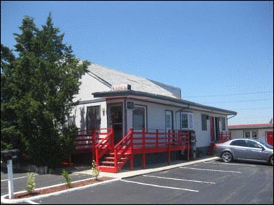 a small house with a red railing in a parking lot at Bay Drive Motel West Atlantic City in West Atlantic City