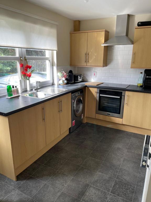 a kitchen with wooden cabinets and a sink and a dishwasher at Fife Apartments in Dunfermline