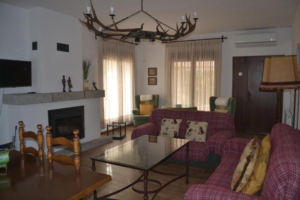 a living room with red couches and a fireplace at Alojamiento Rural Dehesa La Estancia in Andújar