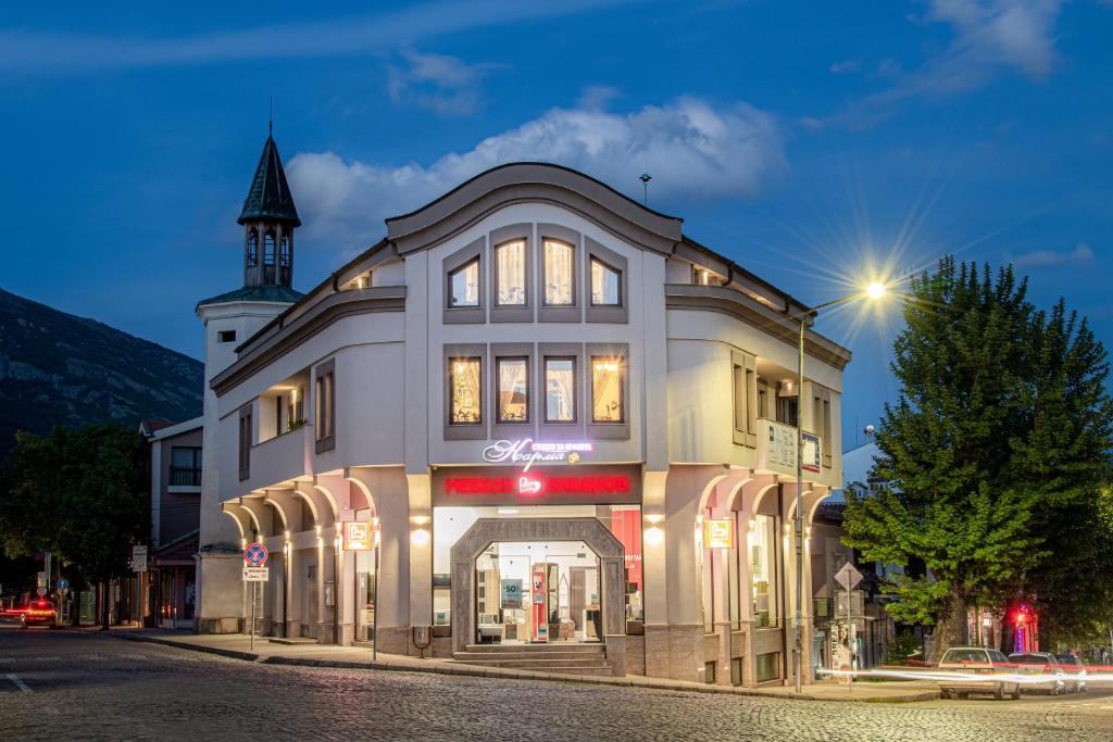 a large building with a clock tower on a street at Hotel Central in Karlovo