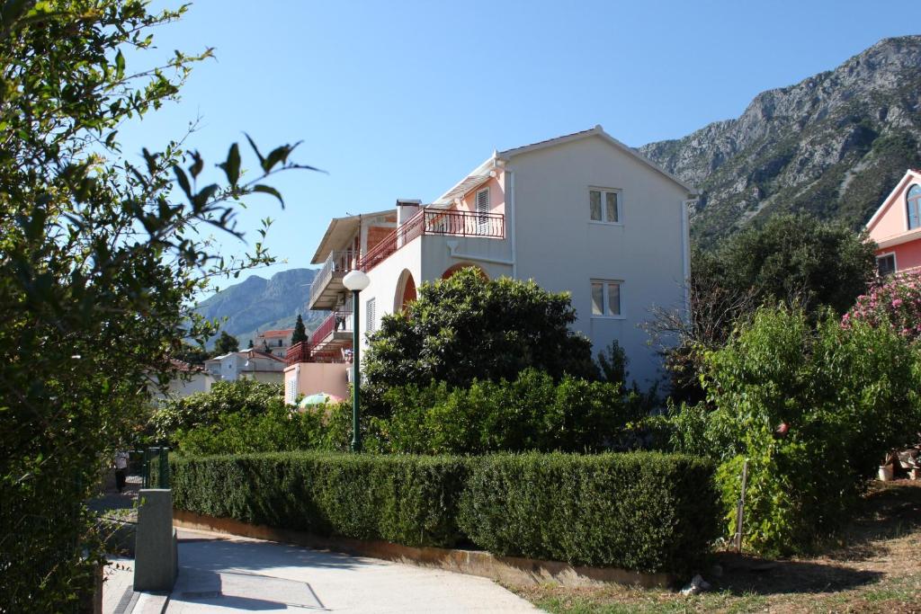 a house with a hedge in front of a mountain at Apartments with a parking space Gradac, Makarska - 6757 in Gradac