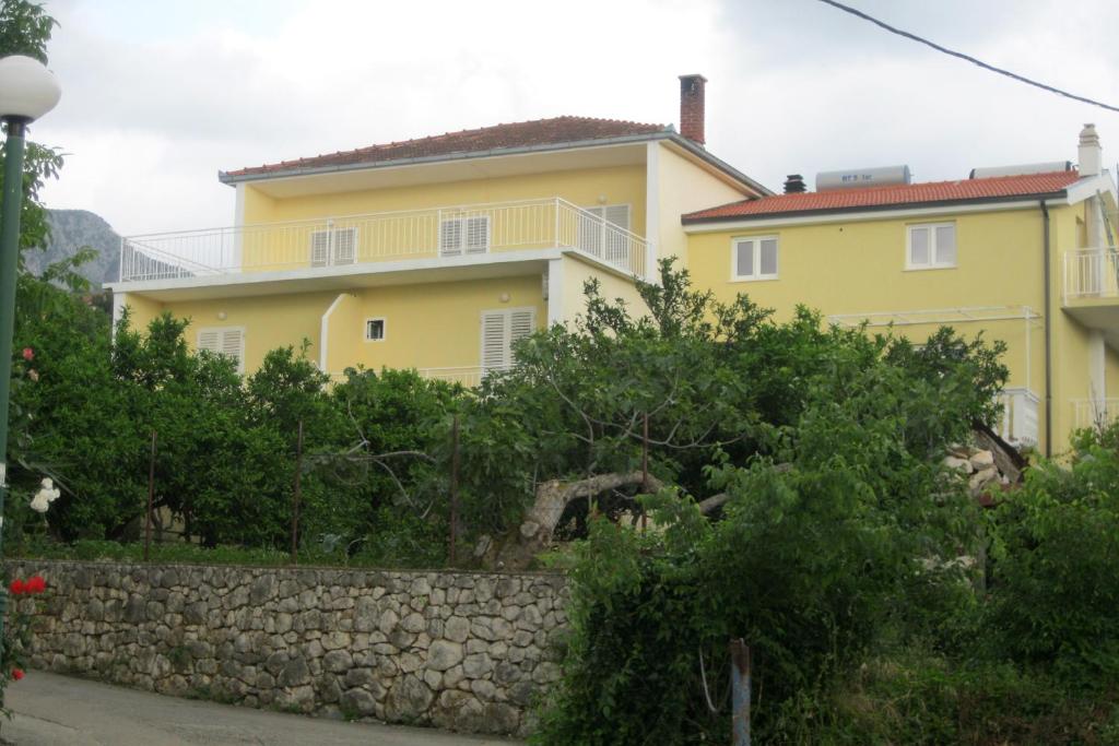 una casa gialla con un muro di pietra di fronte di Apartments by the sea Podaca, Makarska - 6821 a Podaca