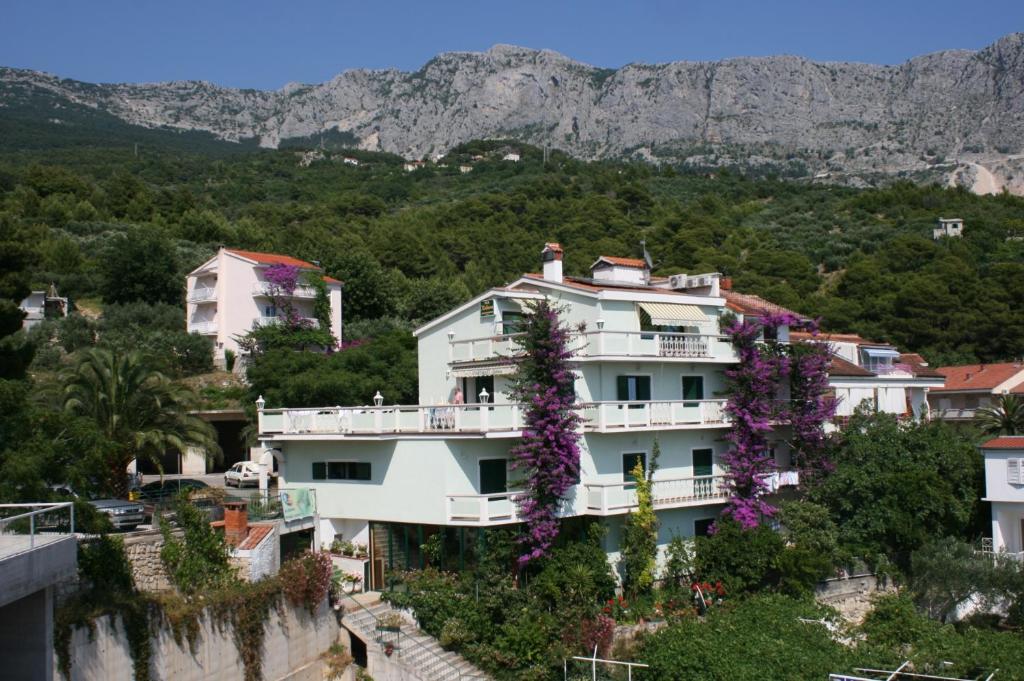 een wit huis met paarse bloemen op een berg bij Apartments and rooms with parking space Podgora, Makarska - 6706 in Podgora