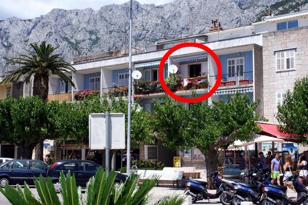 ein roter Kreis auf einem Gebäude mit vor der Tür geparkt in der Unterkunft Apartments by the sea Makarska - 6843 in Makarska