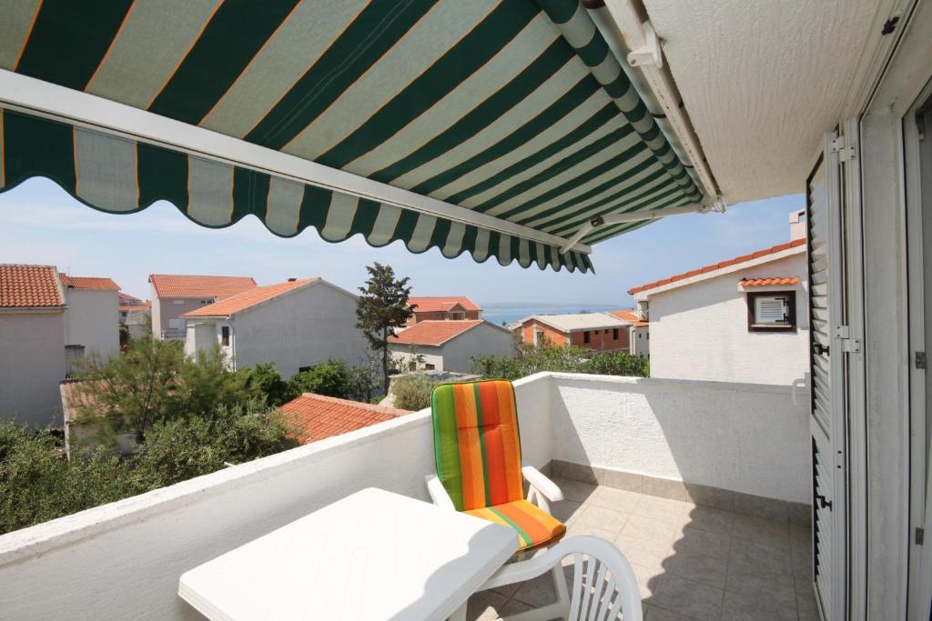 patio z zielono-białym parasolem i krzesłem w obiekcie Apartments with a parking space Povljana, Pag - 6501 w mieście Povljana