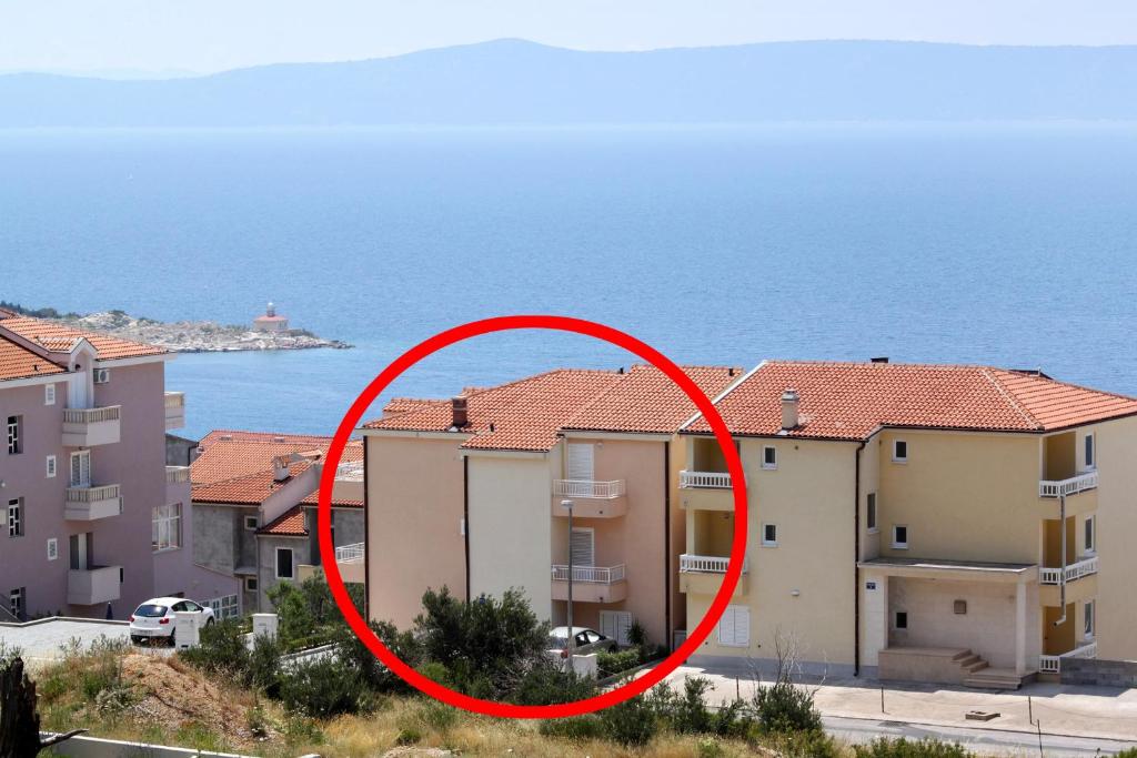 czerwony krąg wokół budynku nad oceanem w obiekcie Apartments with a parking space Makarska - 6667 w Makarskiej