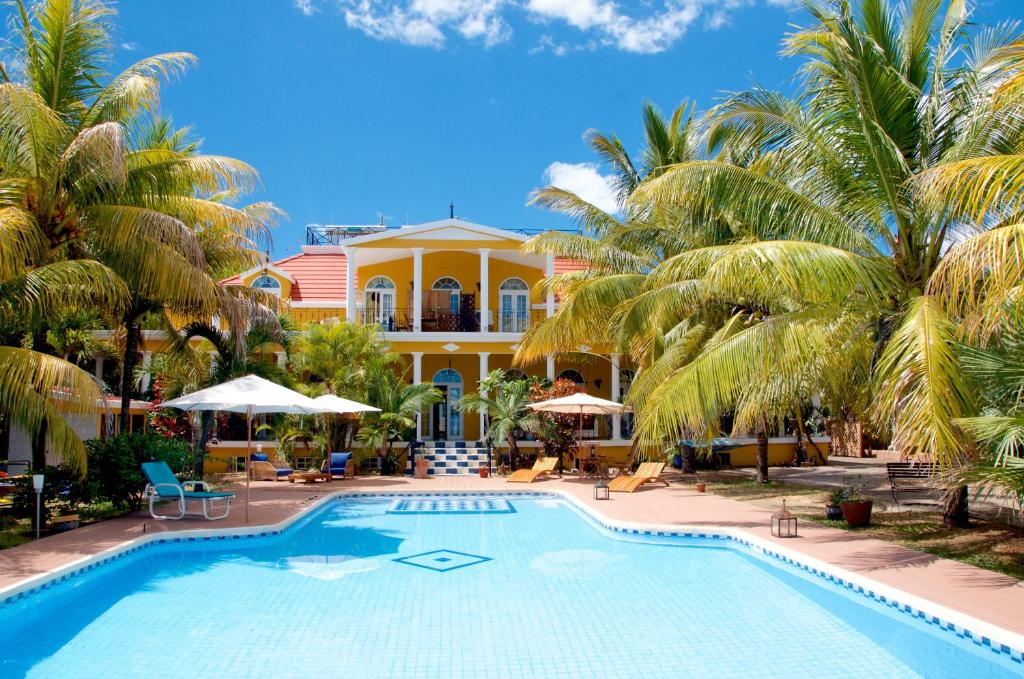 een zwembad voor een huis met palmbomen bij Villa Anakao Mauritius in Port Louis