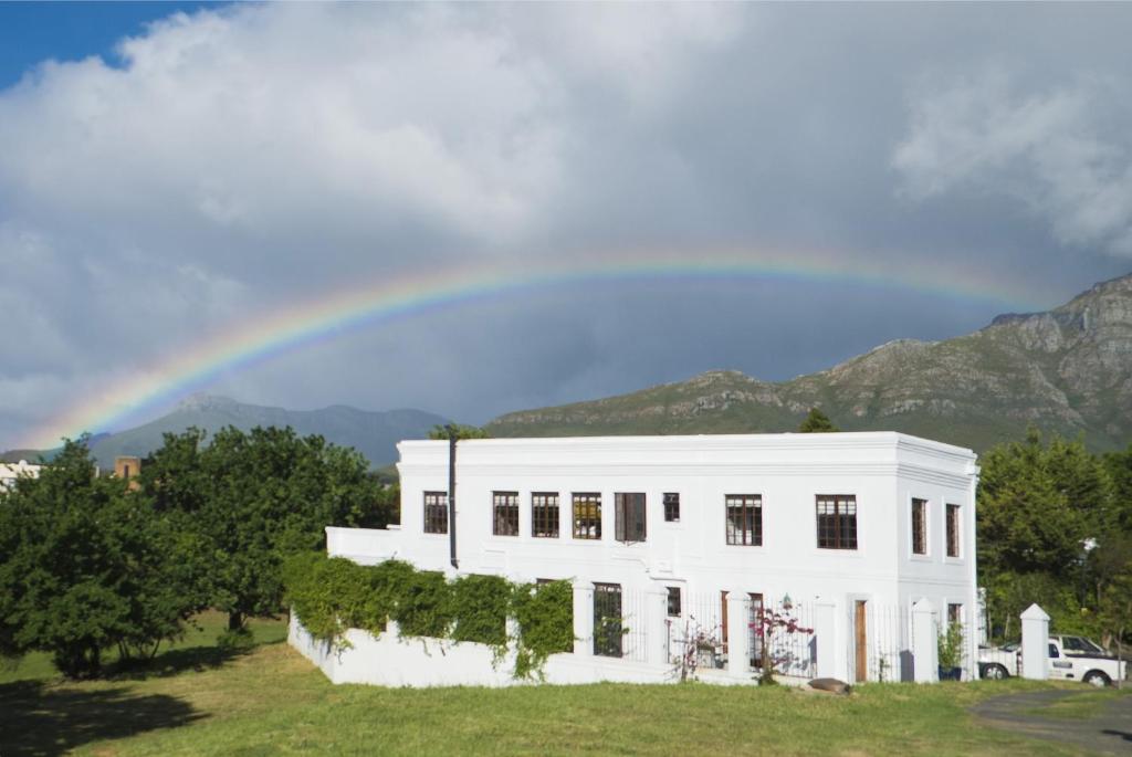 un arco iris sobre una casa blanca con una casa en Boord Guest House, en Stellenbosch