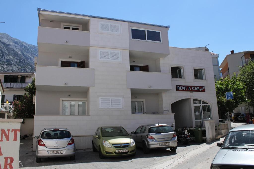 a building with three cars parked in front of it at Apartments by the sea Baska Voda, Makarska - 6848 in Baška Voda