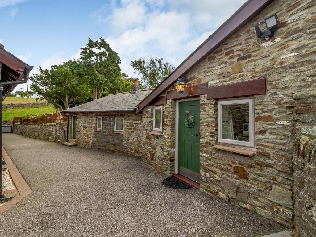 ein Steinhaus mit einer grünen Tür und einer Einfahrt in der Unterkunft Caner Bach Lodge in Bridgend