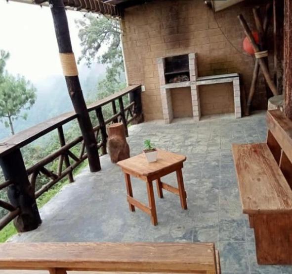eine Terrasse mit einem Tisch und einem Kamin auf einem Gebäude in der Unterkunft Cabañas Campestre Sierra Viva in Zacatlán