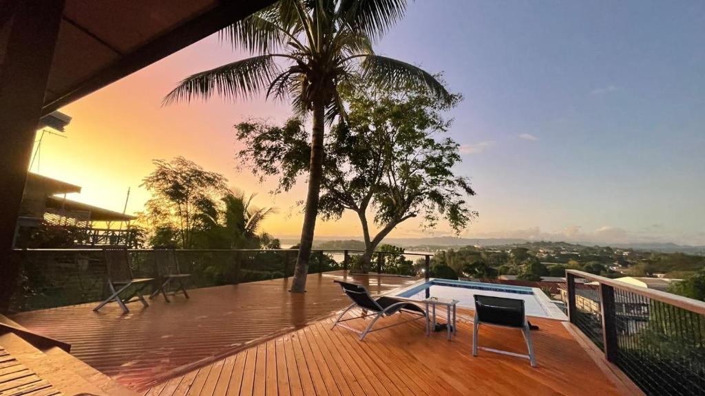 eine Terrasse mit Stühlen, einem Pool und einer Palme in der Unterkunft Bamboo Villa in Port Vila