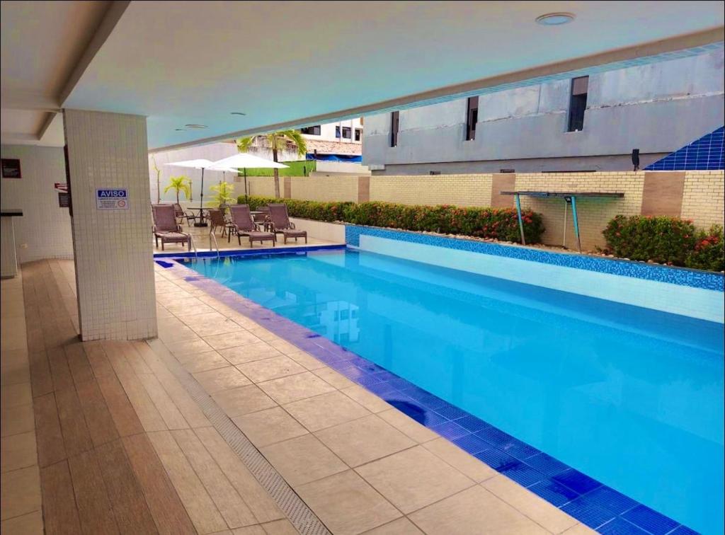 a large swimming pool with blue water in a building at Flat beira mar Tambaú in João Pessoa