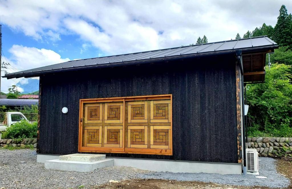 Nikko Cottage Yurt في نيكو: مبنى أسود صغير وأبواب خشبية عليه