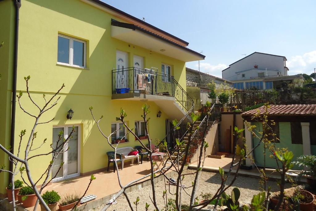 a yellow house with stairs and a balcony at Apartments by the sea Funtana, Porec - 6905 in Funtana