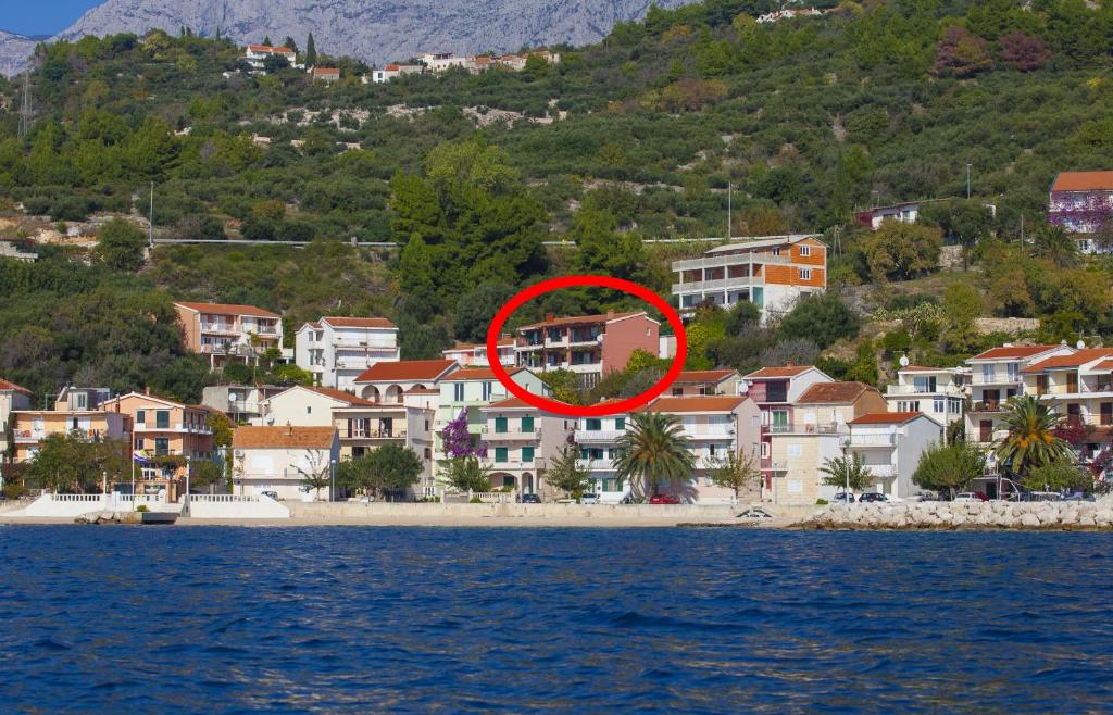 a red circle sitting on a beach next to houses at Apartments by the sea Podgora, Makarska - 6673 in Podgora