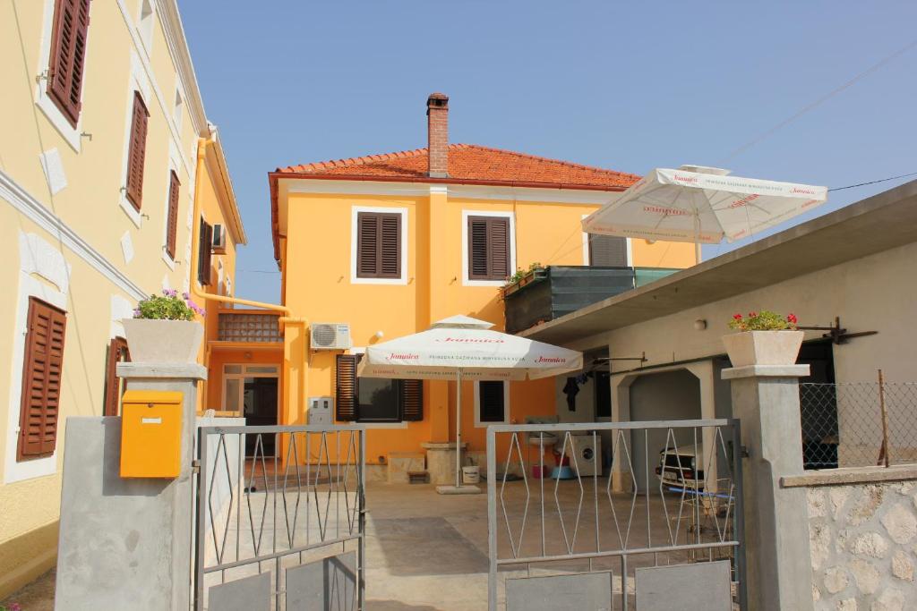 a house with a gate and an umbrella at Apartments by the sea Pasman - 8295 in Pašman