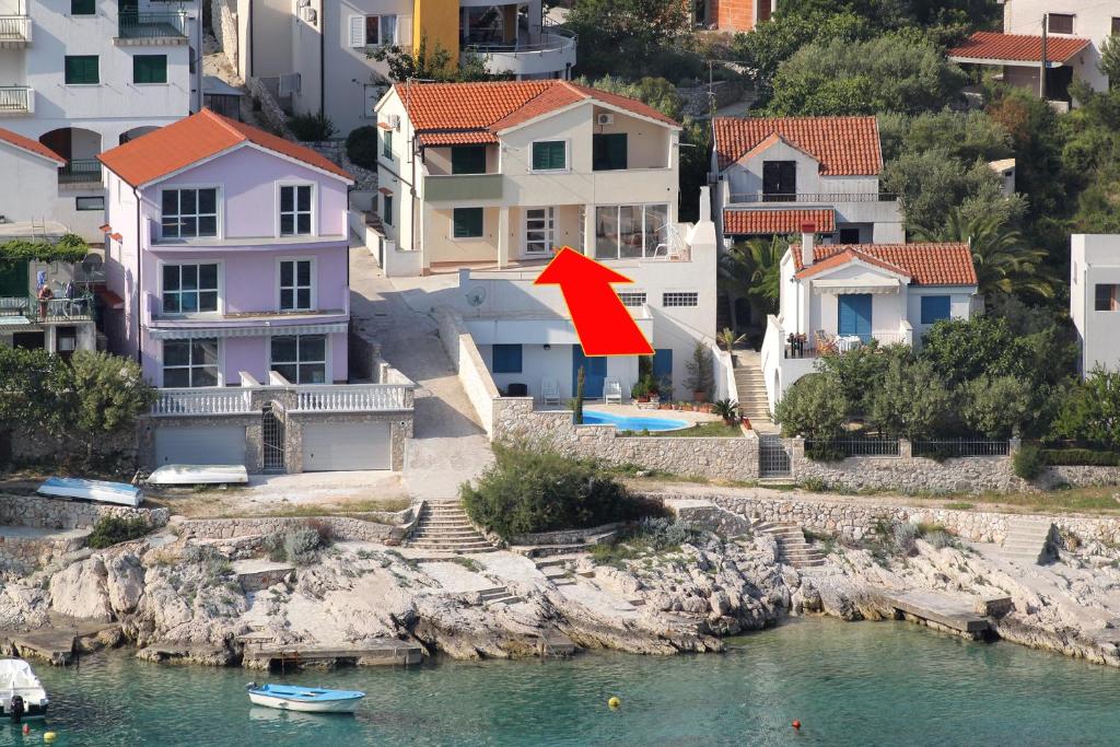 uma seta vermelha apontando para uma casa ao lado da água em Apartments by the sea Bilo, Primosten - 8364 em Primošten