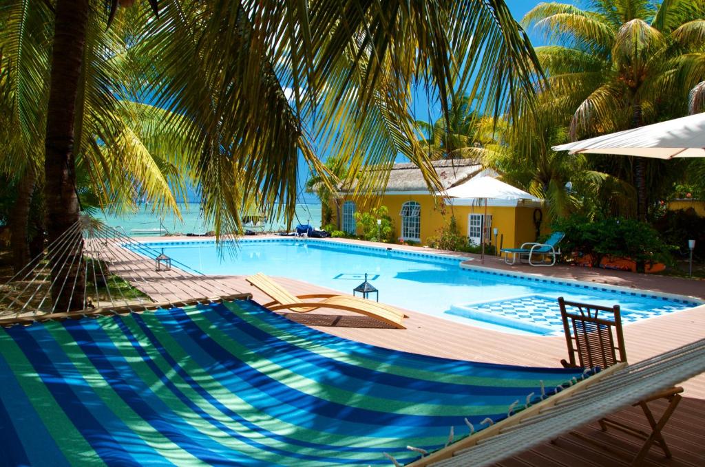 a large swimming pool with a hammock and palm trees at Villa Anakao Mauritius in Port Louis