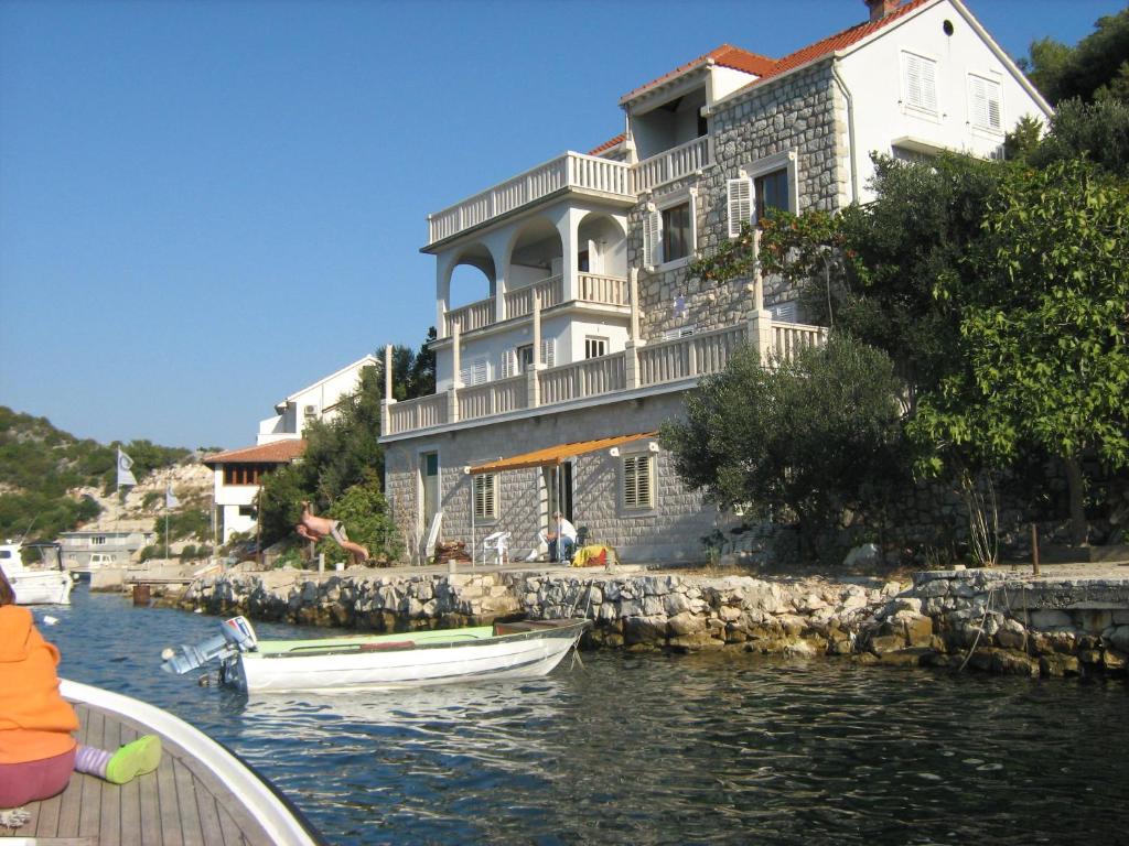 a large white house with two boats in the water at Apartments by the sea Zaklopatica, Lastovo - 8346 in Lastovo
