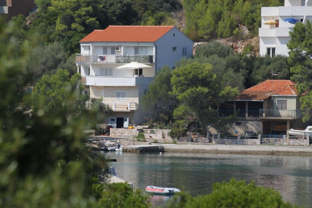 une maison avec un toit rouge à côté de l'eau dans l'établissement Apartments by the sea Pasadur, Lastovo - 8351, à Ubli