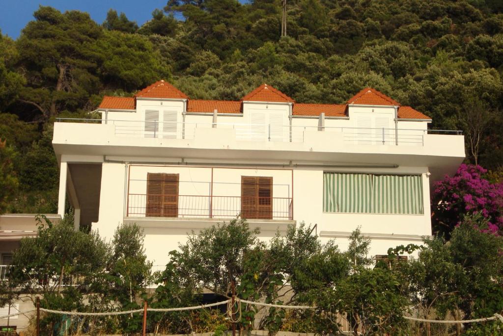 a white house in front of a mountain at Apartments by the sea Ubli, Lastovo - 8354 in Ubli