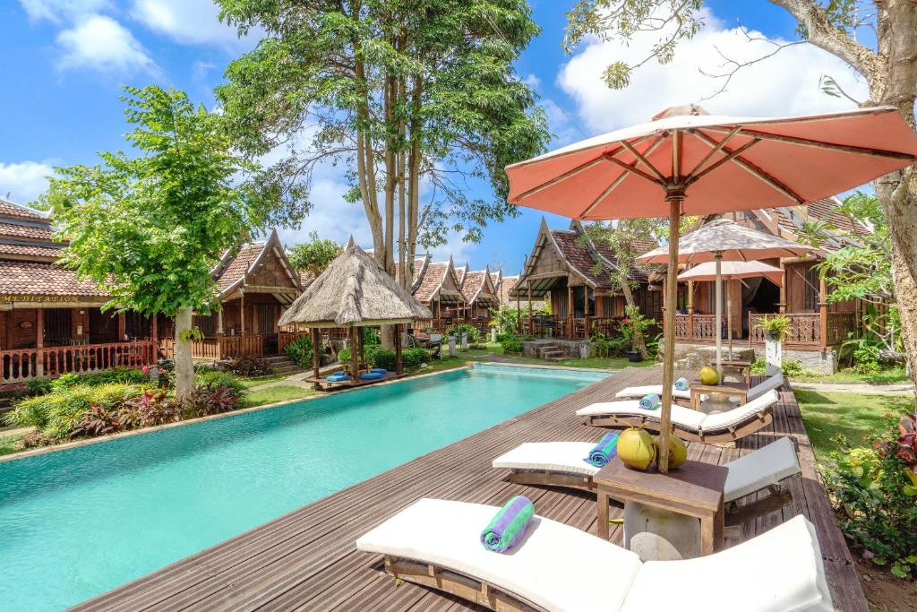 烏魯瓦圖的住宿－My Dream Bali，一张带椅子和遮阳伞的度假村游泳池的图片