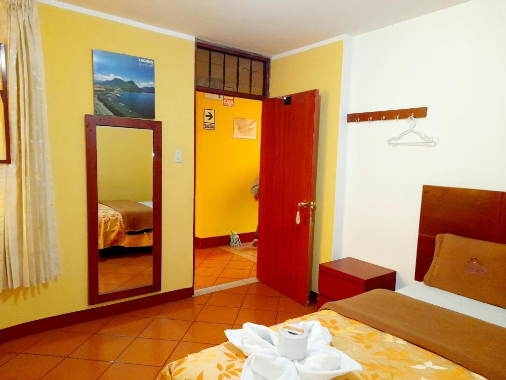 Habitación con 2 camas, espejo y 1 dormitorio. en Hospedaje Las Lilas, en Huancayo