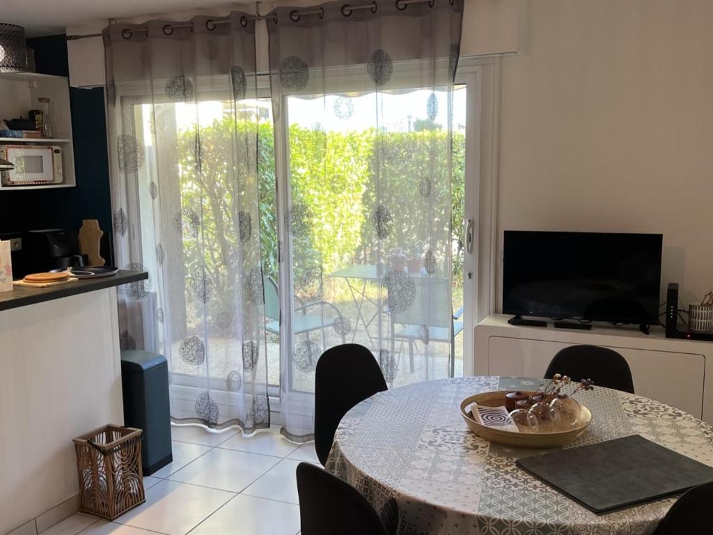 une cuisine et une salle à manger avec une table et une télévision dans l'établissement Appartement T2 avec Jardin, Proche Plage et Centre, Parking Privé, Animaux Acceptés, Wi-Fi Gratuit - FR-1-487-342, à Cabourg