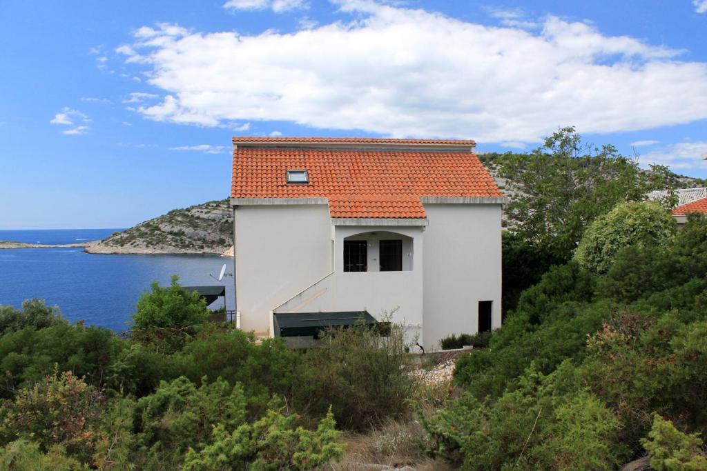 a white house with an orange roof on a hill next to the water at Apartments by the sea Razanj, Rogoznica - 8365 in Rogoznica