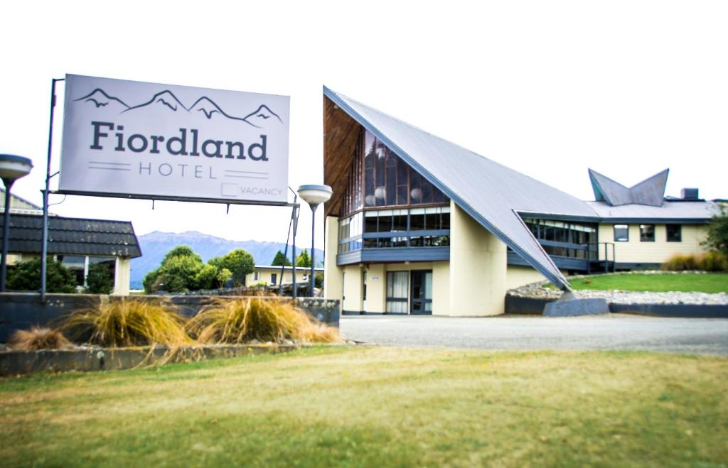 a hotel with a sign in front of a building at Fiordland Hotel in Te Anau
