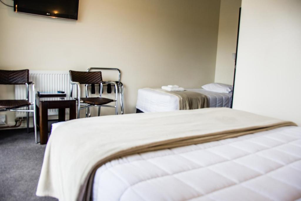 um quarto de hotel com duas camas e uma mesa e uma cadeira em Fiordland Hotel em Te Anau