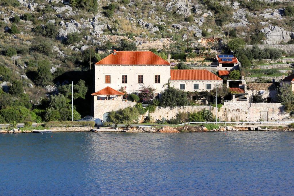 a white building with a red roof next to the water at Seaside house with a swimming pool Mokosica, Dubrovnik - 8583 in Mokošica