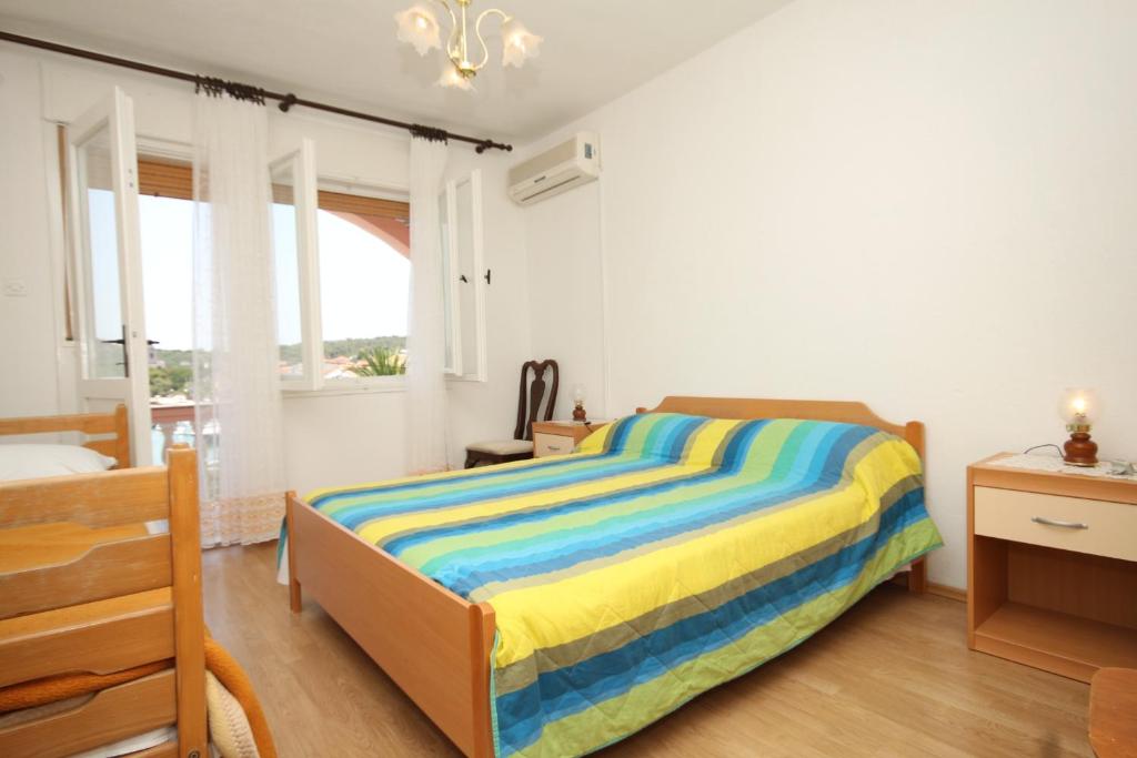sypialnia z łóżkiem z kolorowym kocem w paski w obiekcie Apartments by the sea Kukljica, Ugljan - 8318 w mieście Kukljica