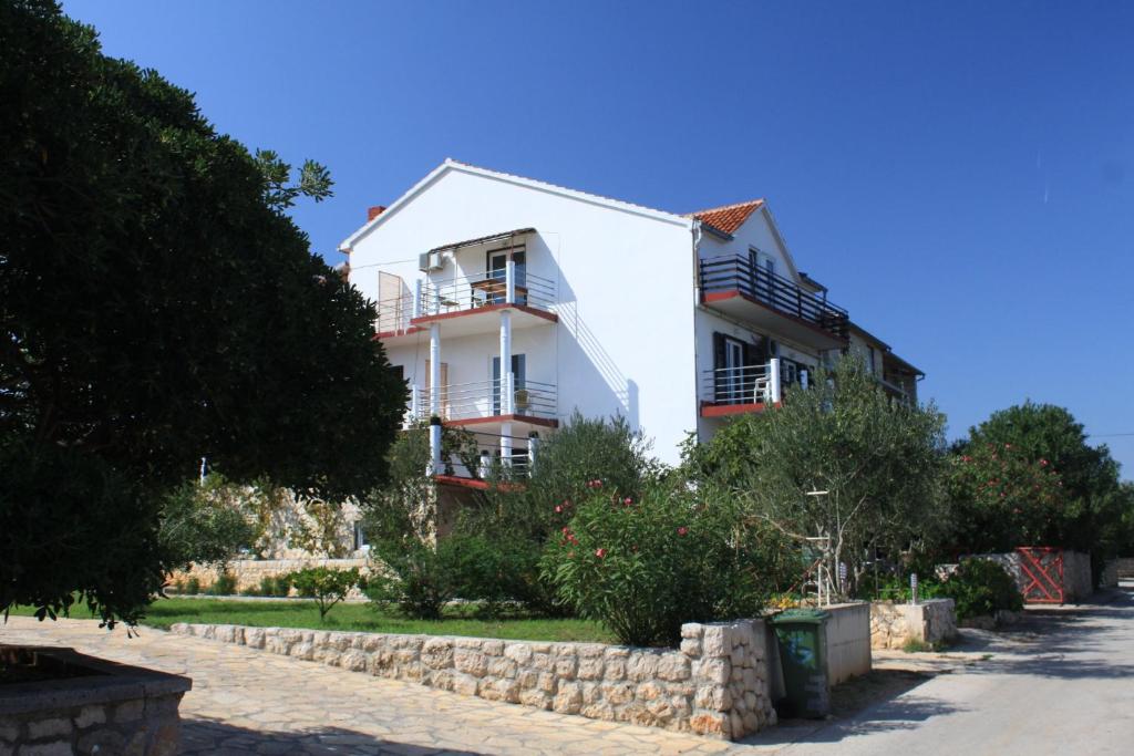 una casa blanca con una pared de piedra delante de ella en Apartments by the sea Tkon, Pasman - 8458, en Tkon