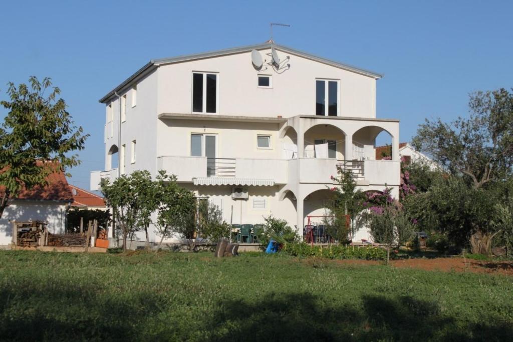 a large white house with a yard in front of it at Apartments by the sea Mrljane, Pasman - 8463 in Neviđane