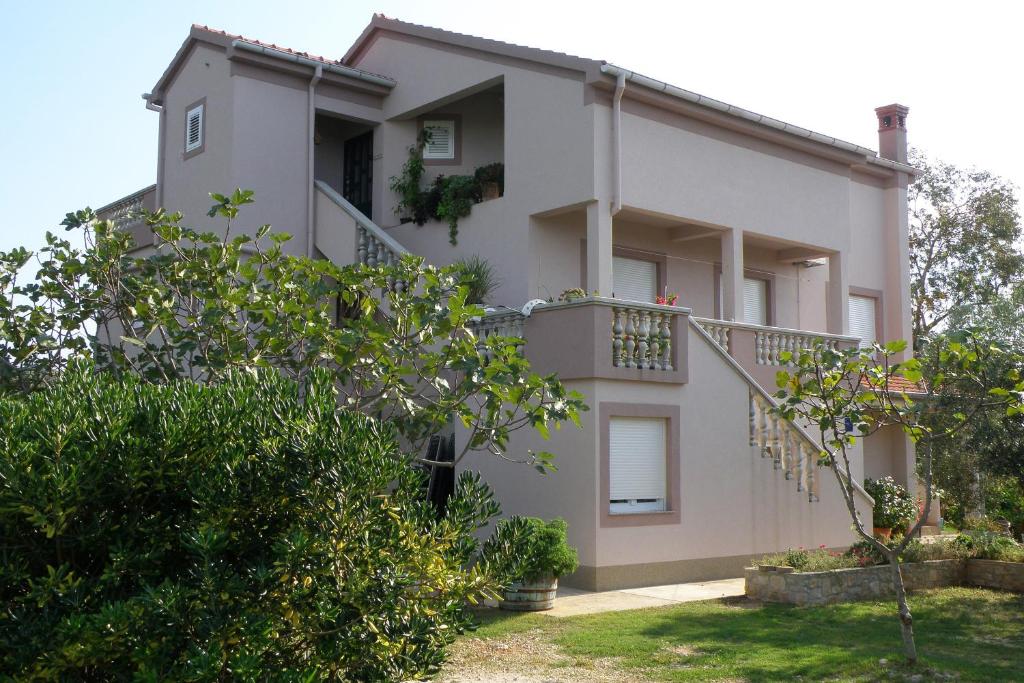 une maison blanche avec un balcon et quelques arbres dans l'établissement Apartments by the sea Ugljan - 8468, à Ugljan