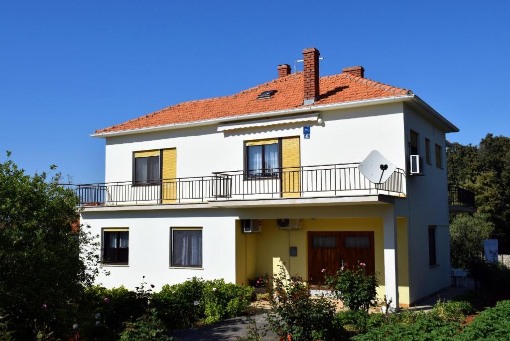 uma grande casa branca com uma varanda em Apartments with a parking space Ugljan - 8493 em Ugljan