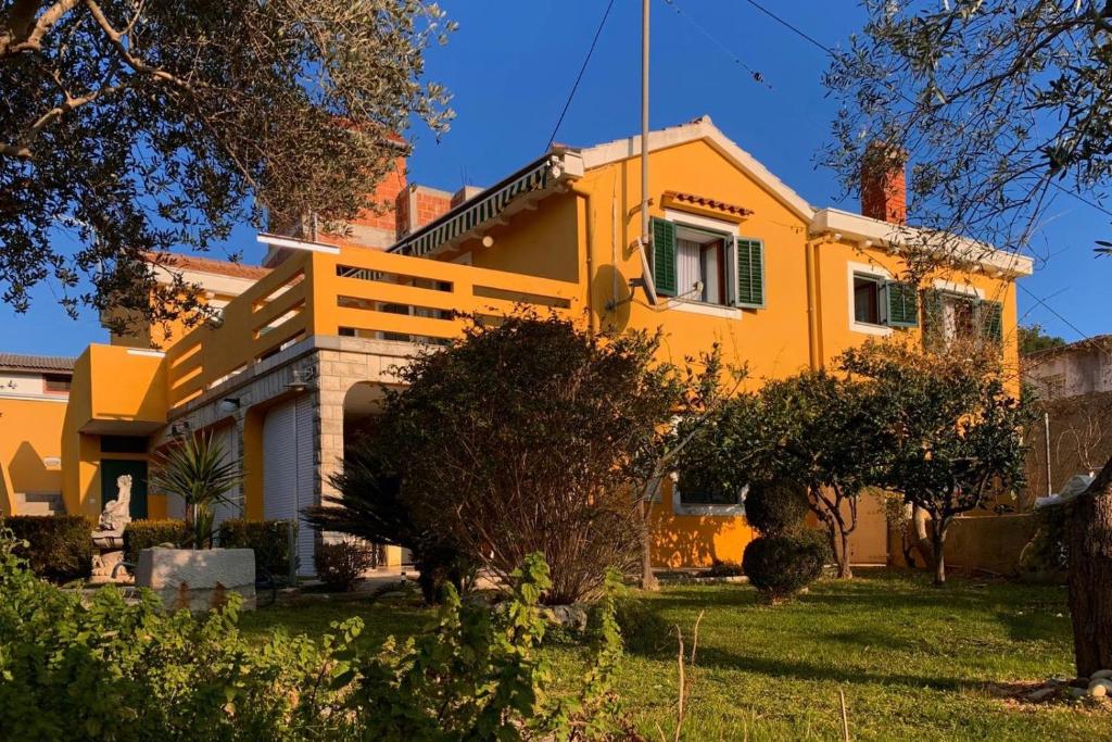 ein gelbes Haus mit Bäumen davor in der Unterkunft Apartments by the sea Kukljica, Ugljan - 8293 in Kukljica