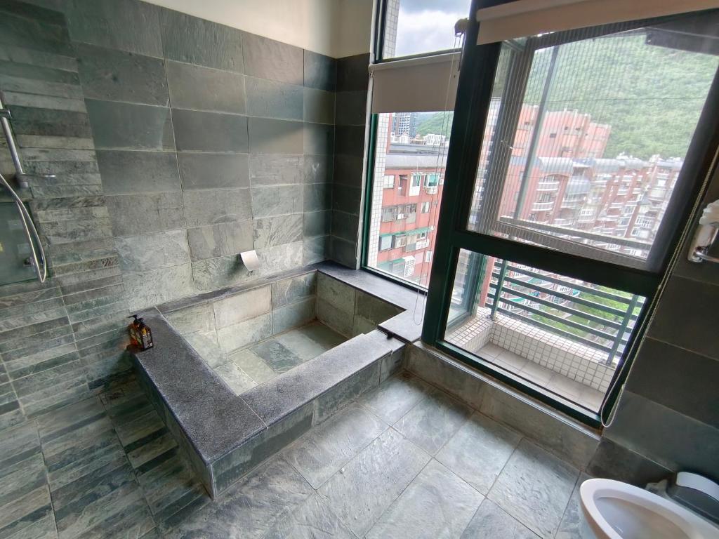 baño con bañera y ducha con ventana en 礁嬉湯宿spring en Jiaoxi