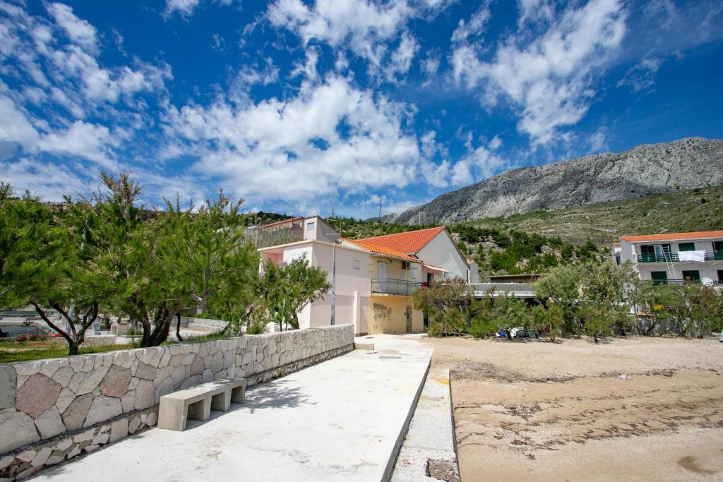 a stone retaining wall and a bench in front of a building at Family friendly seaside apartments Duce, Omis - 8668 in Duće