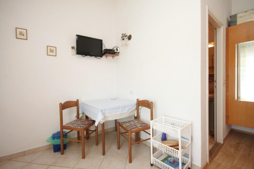 stół jadalny z krzesłami i telewizor na ścianie w obiekcie Apartments and rooms by the sea Kukljica, Ugljan - 8408 w mieście Kukljica