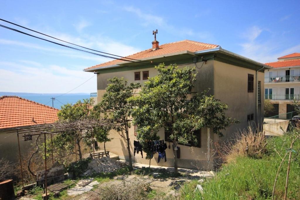 une maison avec un arbre en face dans l'établissement Apartments by the sea Suhi Potok, Omis - 8676, à Dugi Rat