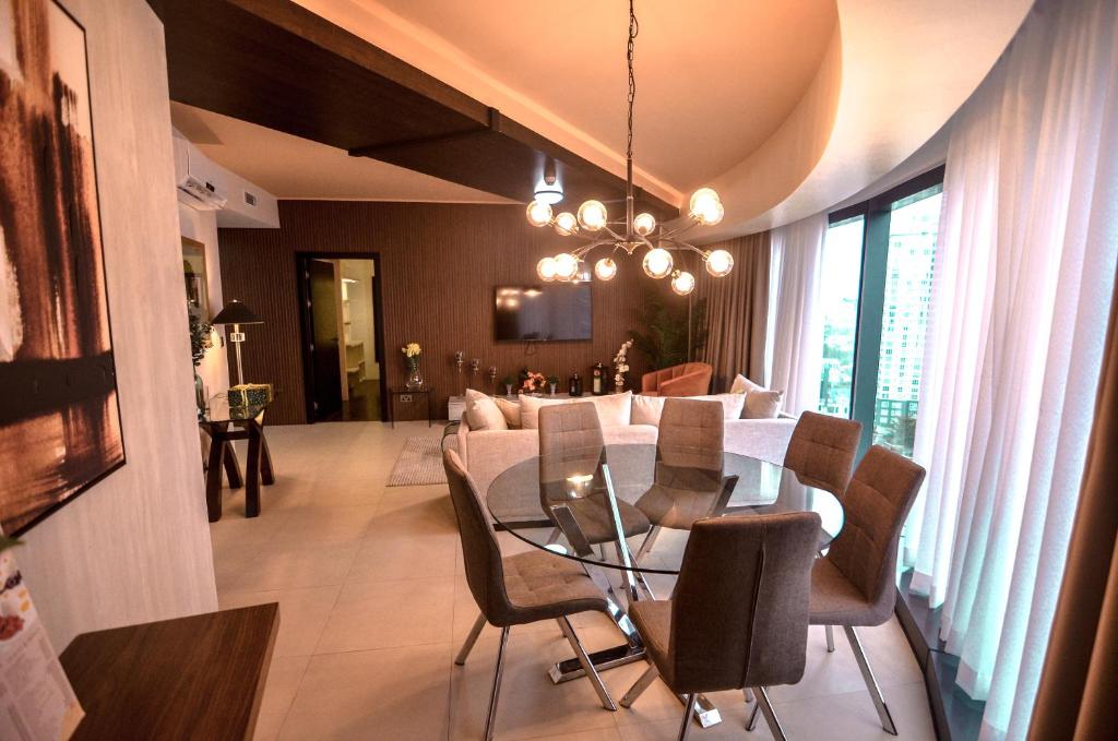 a dining room and living room with a table and chairs at AEON SUITES STAYCATION managed by ARIA HOTEL in Davao City