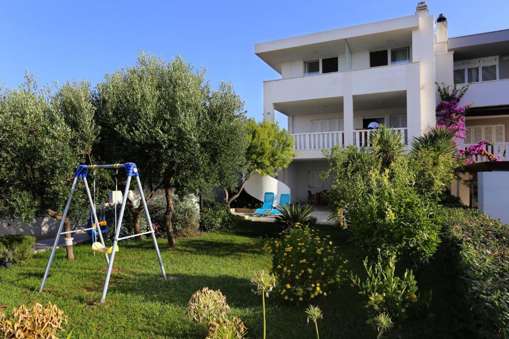 a yard with a swing in front of a house at Apartments by the sea Zecevo Rtic, Rogoznica - 10333 in Rogoznica