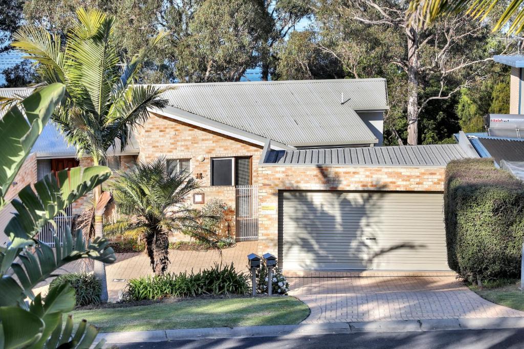 a house with a garage and a palm tree at LAKESIDE2 in Merimbula