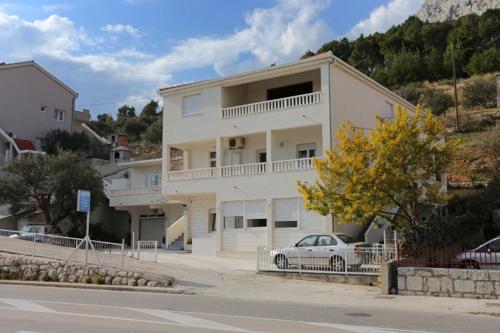 ein weißes Haus mit einem davor geparkt in der Unterkunft Apartments with a parking space Omis - 10351 in Omiš